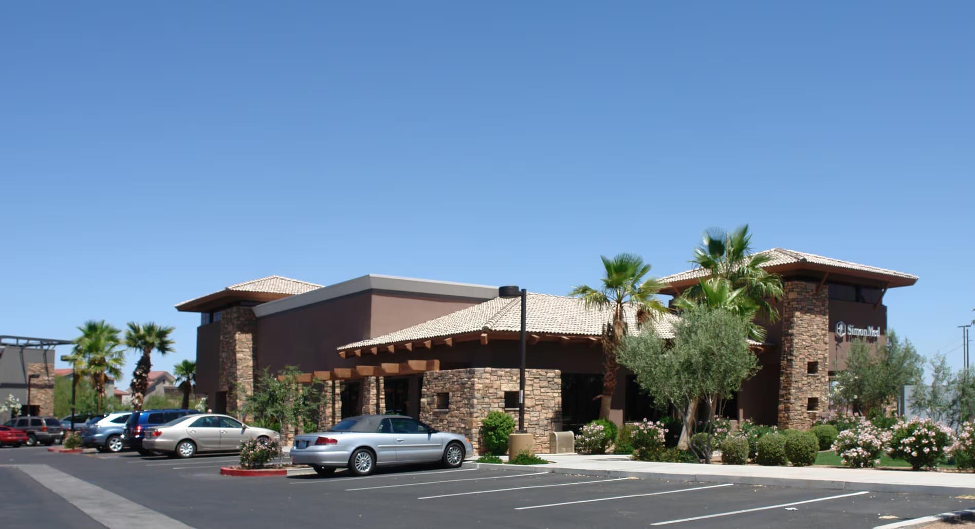 Modern building with palm trees and parking.